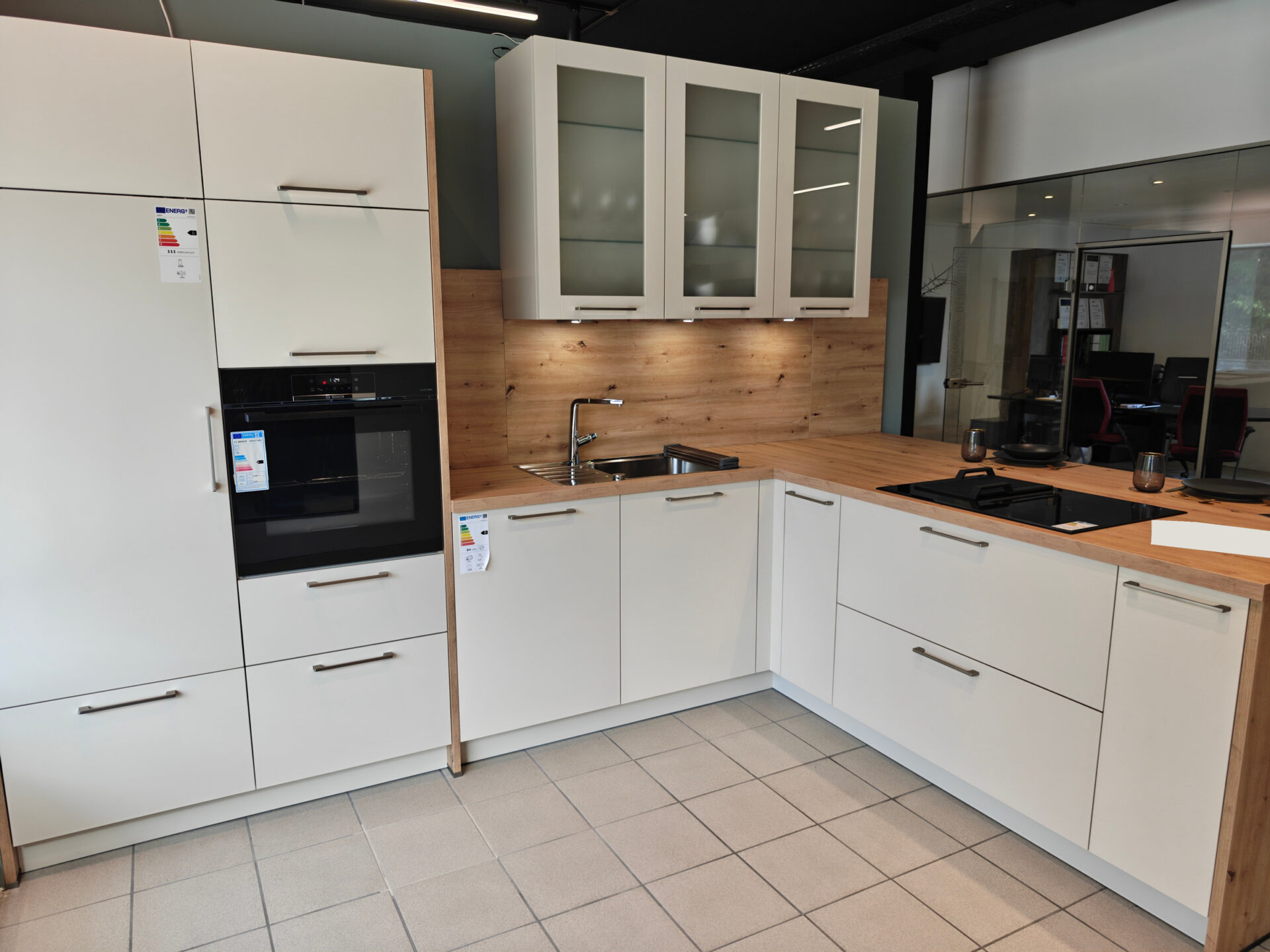 Gesamtansicht der Küche in Crema-Magnolie mit Holzoptik und Kochhalbinsel