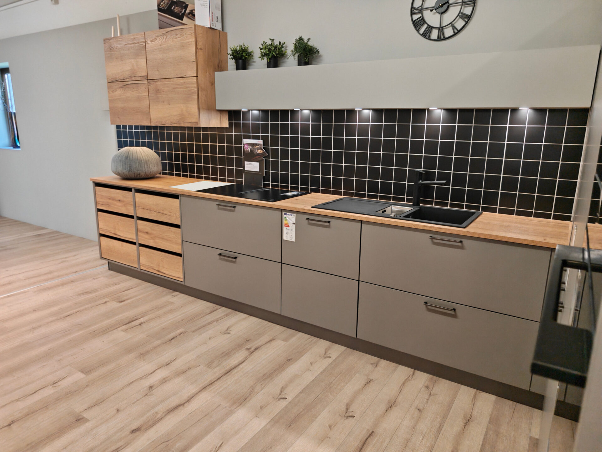 Spül- und Kochzeile mit Holzschubladen und schwarzer Fliesenrückwand