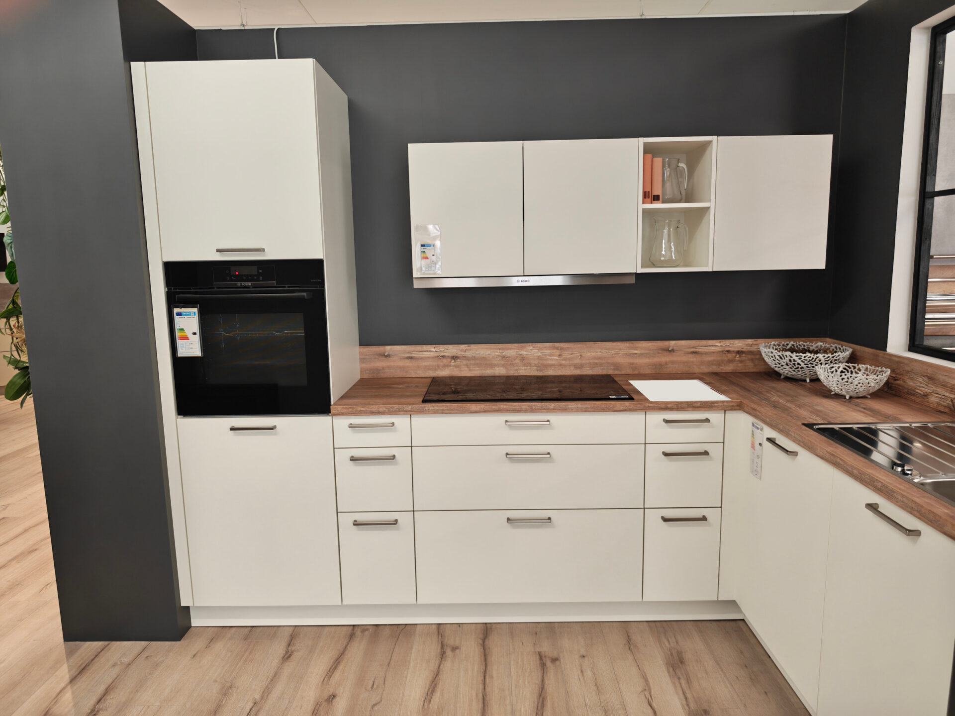 Kochbereich der weißen Häcker-Küche mit Bosch-Backofen und Holzoptik-Arbeitsplatte